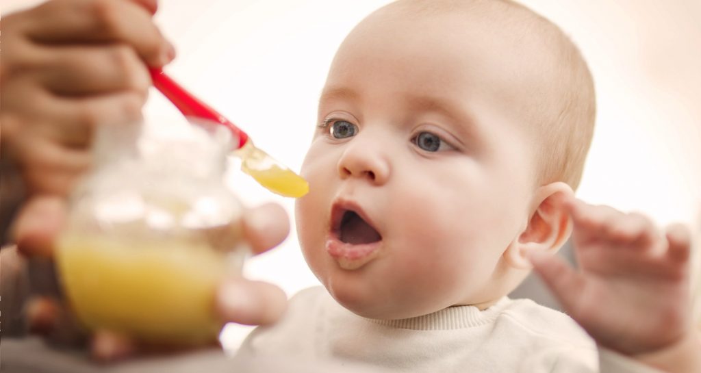 Baby getting fed gerber baby food