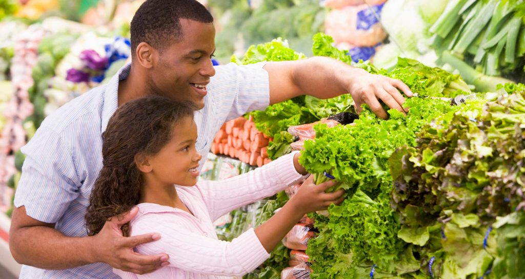 father and daughter selecting vegetables in a market