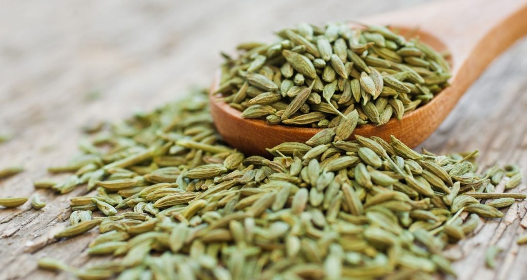 wooden spoon of spice seeds on a wooden table