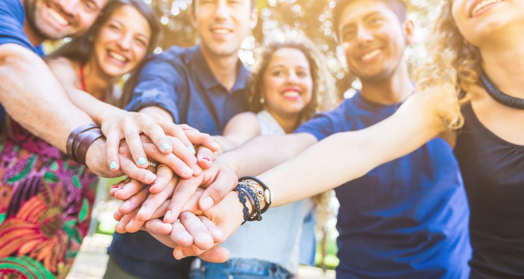 group of people with their hands on top of each other in circle