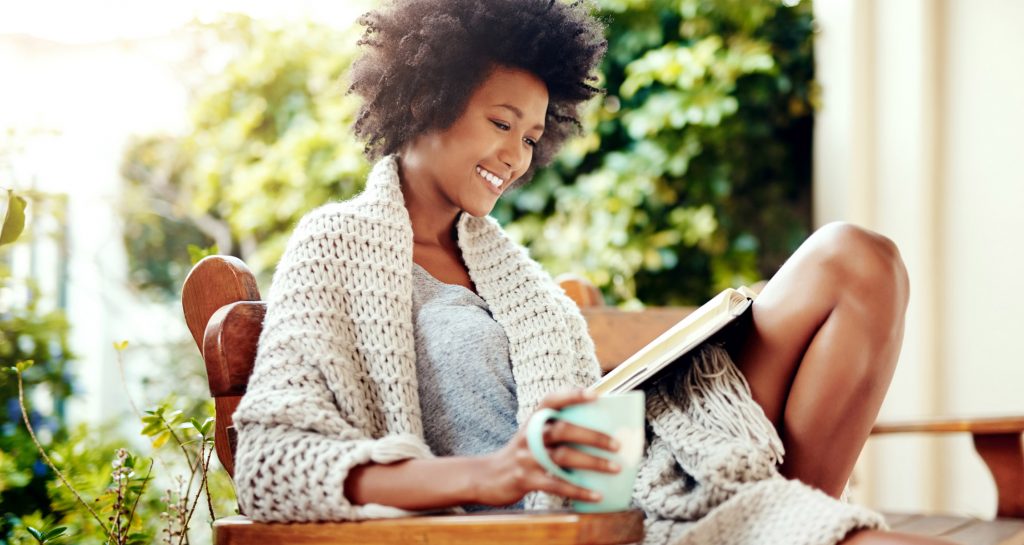 Woman reading a book on a bench outside